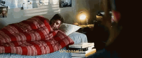 a man is laying on a bed with a red and white striped blanket and a stack of books .