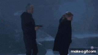a man holding a gun and a woman walking in the dark with make a gif.com at the bottom