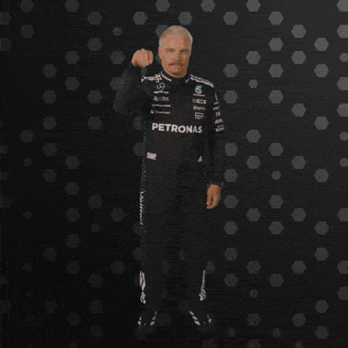 a man with a mustache is wearing a petronas racing suit