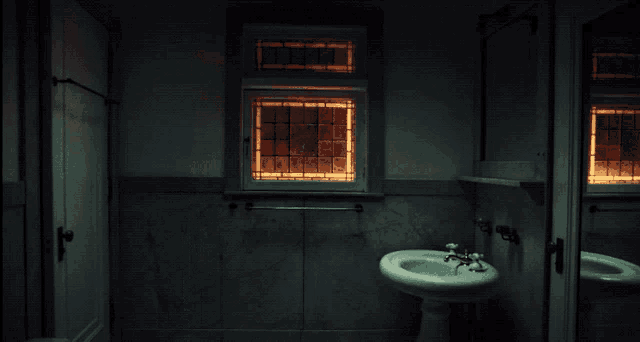 a bathroom with a sink and a window that is lit up