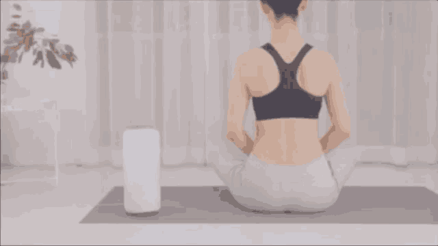 a woman sits on a yoga mat with her legs crossed