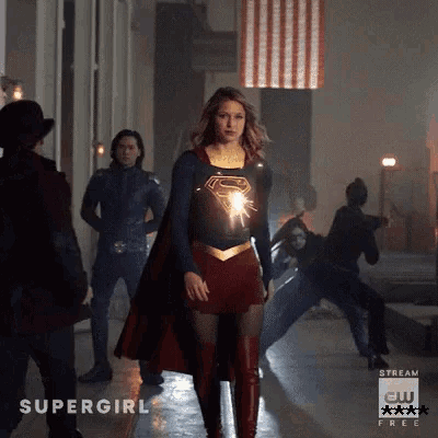 a woman in a supergirl costume is standing in front of people