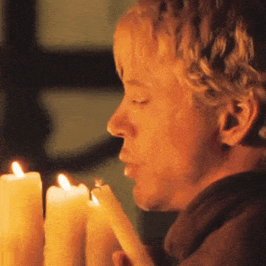 a close up of a man holding a lit candle with his eyes closed