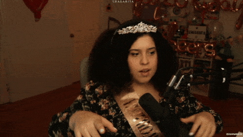 a woman wearing a sash that says bachelorette is speaking into a microphone