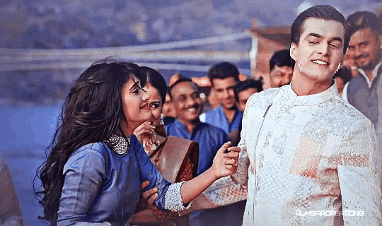 a man and a woman are standing in front of a crowd with a caption that says ' bollywood ' at the bottom