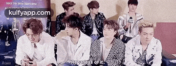 a group of young men are sitting next to each other in a room and one of them is talking into a microphone .