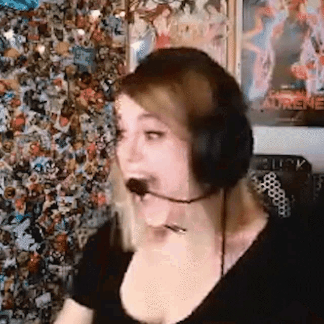 a woman wearing headphones and a microphone is laughing in front of a wall of pictures .