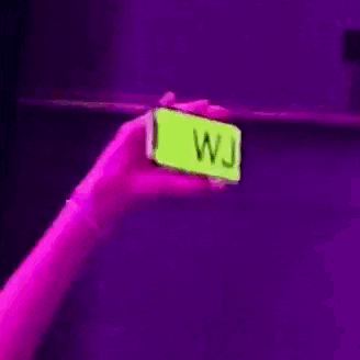 a person is holding a neon sign that says wjsk in their hand .