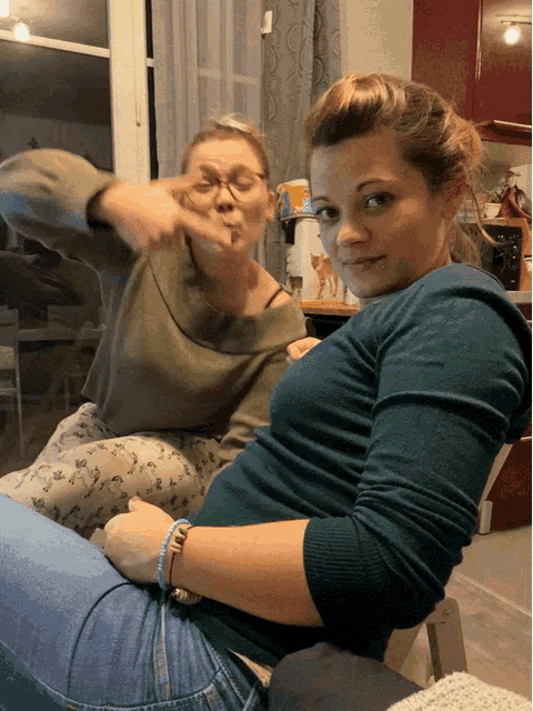 a woman in a green sweater is sitting next to another woman in a grey sweater