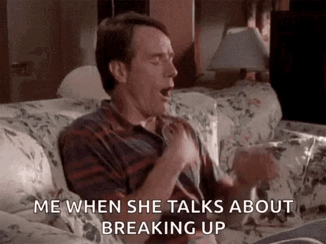 a man is sitting on a couch yawning while talking to a woman .