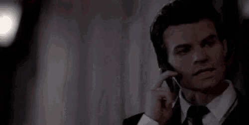 a close up of a man in a suit and tie talking on a cell phone .