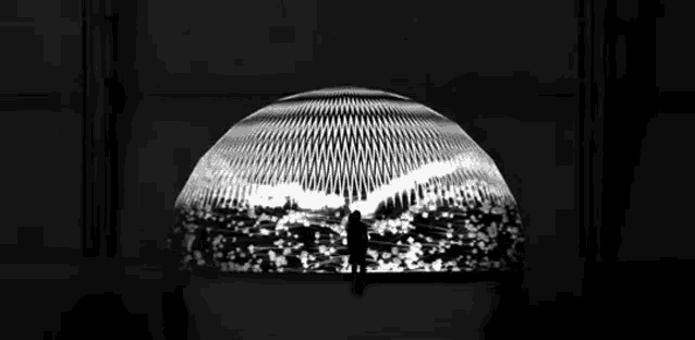 a silhouette of a man standing in front of a large dome .