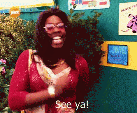 a woman wearing sunglasses and a red sweater is smiling and saying see ya
