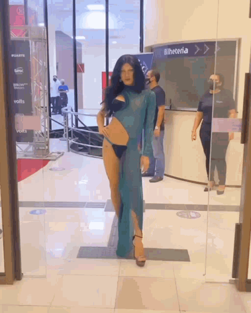 a woman in a blue dress is standing in front of a ticketeria counter
