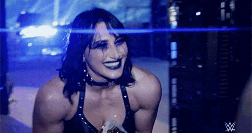 a female wrestler is smiling in front of a w logo