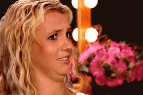 britney spears is making a funny face in front of a bunch of pink flowers