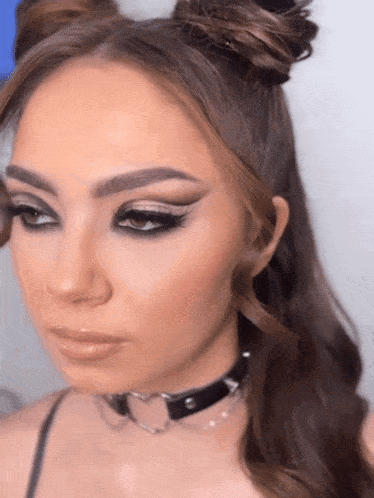 a close up of a woman 's face wearing a choker and buns