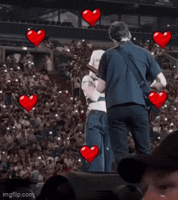 a man playing a guitar next to a woman in front of a crowd