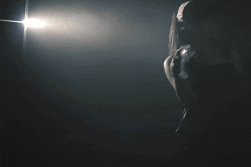 a silhouette of a woman in a dark room holding a light
