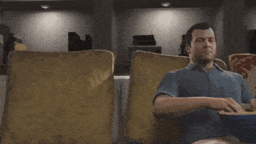 a man is sitting on a couch with a bowl of popcorn in his hand