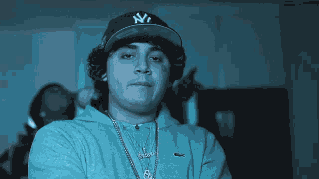 a man wearing a ny hat and a necklace