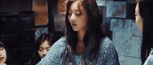 a woman in a blue sweater is sitting in a room with other women .