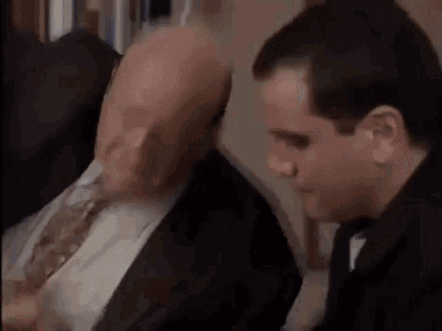 a man in a suit and tie is talking to another man .