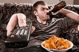 a man is sitting on a couch drinking a beer and eating chips while holding a remote control .
