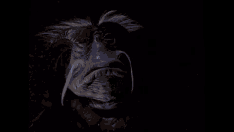 a woman in a blue shirt is standing in the dark .