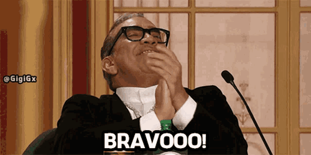 a man in a suit and tie is clapping with the word bravooo written below him
