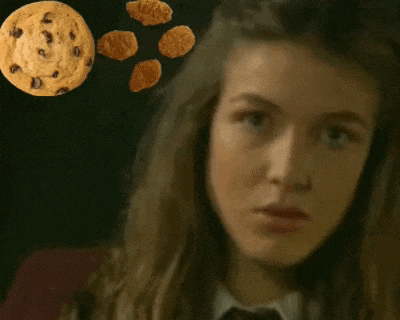 a girl is looking at a chocolate chip cookie
