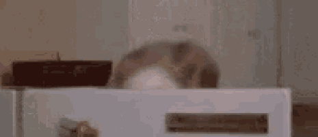 a woman with a white mask on her face is sitting in front of a microwave with her mouth open .