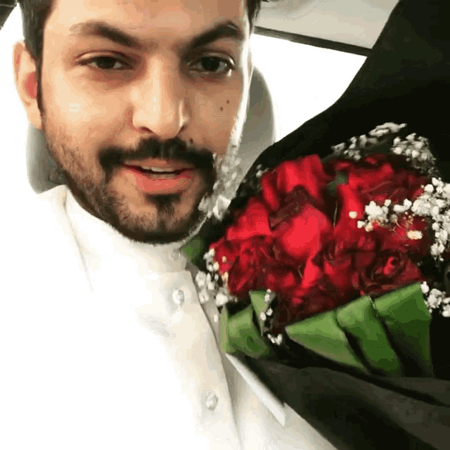a man holding a bouquet of red roses with baby 's breath