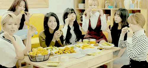 a group of young women are sitting around a table eating food .