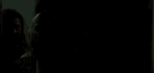 a man is holding a gun with flames coming out of it in a dark room .