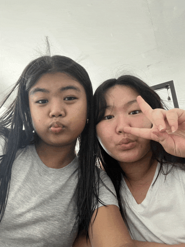 two girls are posing for a picture and one of them is giving a peace sign