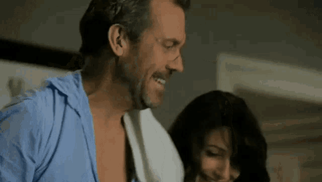 a man and a woman are standing next to each other in a room and smiling .
