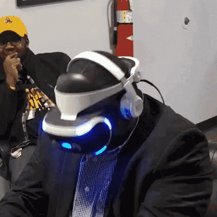 a man wearing a virtual reality headset is sitting next to another man