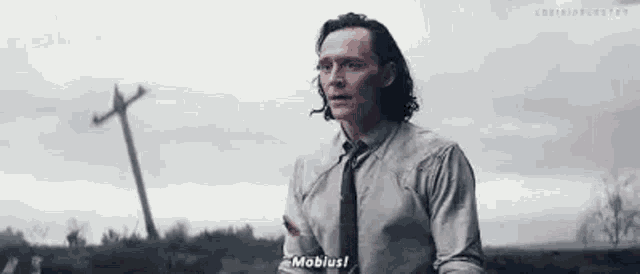 a man in a suit and tie is standing in a field talking to a woman .