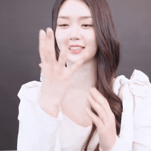 a woman in a white blouse is clapping her hands .