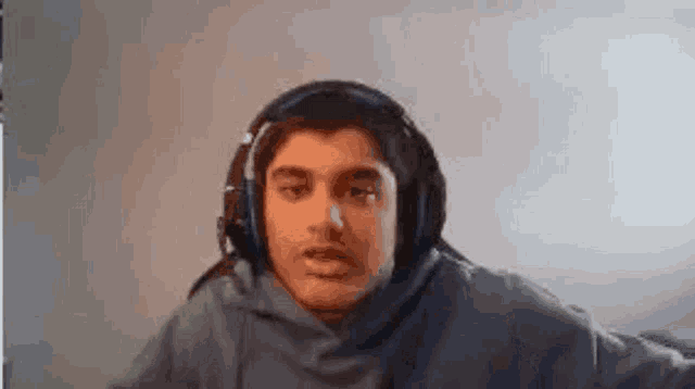 a man wearing headphones and a hoodie is looking at the camera .