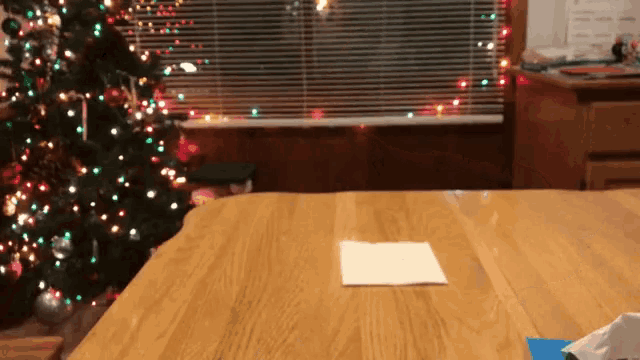 a christmas tree is behind a wooden table with a napkin on it
