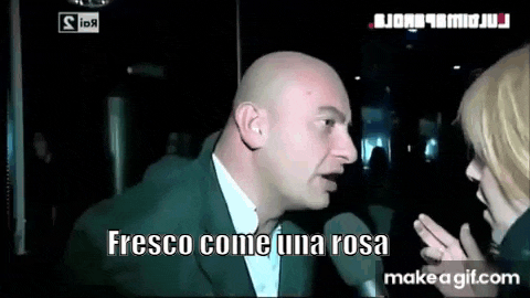 a bald man in a suit is talking into a microphone while a woman looks on .