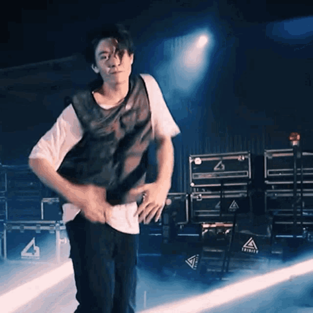 a man is dancing on a stage in front of a stack of boxes that say trinity