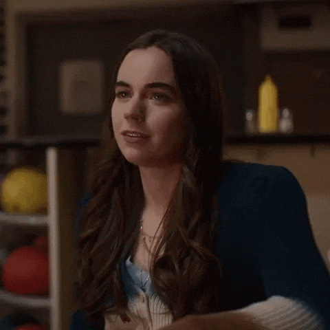 a woman is sitting at a table in a bowling alley and says okay .