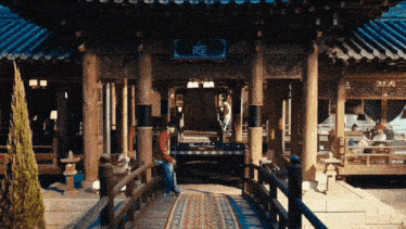 a man stands in front of a building with chinese writing on the roof