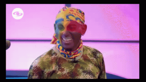 a man wearing a camouflage shirt and a colorful headband with the letter c on it