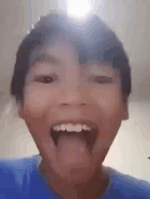 a young boy is sticking his tongue out in a funny face .