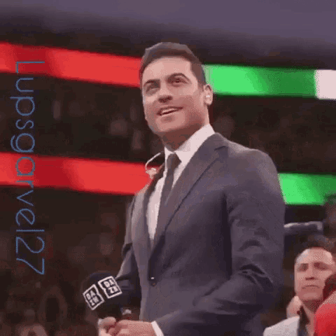 a man in a suit and tie is smiling and dancing in front of a crowd .