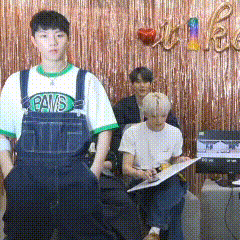 a man wearing overalls and a paws shirt stands in front of a group of people .